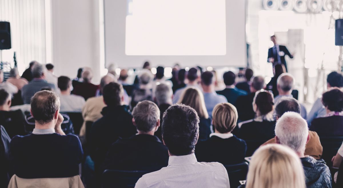 Stock picture showing an group of people listening to a presenter  